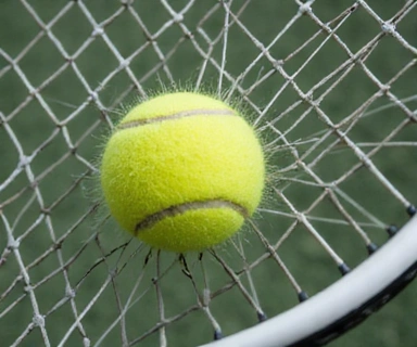 Close-up of a tennis racket hitting a tennis ball